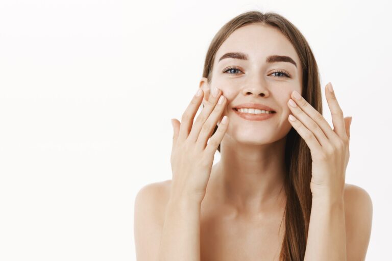 encantadora-mujer-joven-relajada-suave-haciendo-procedimiento-cosmetologico-aplicando-crema-facial-cara-dedos-sonriendo-ampliamente-sintiendose-perfecta-cuidando-piel-min-scaled